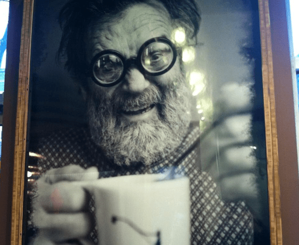 a bearded man in goggle eye glasses really enjoying his coffee